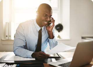 Image of a man talking on the phone while looking at his computer